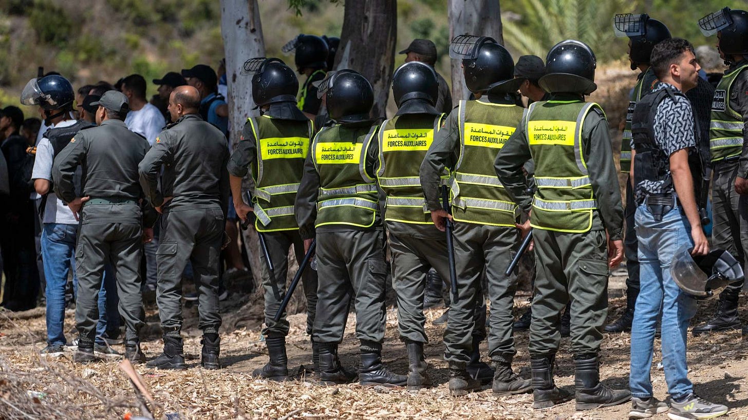 Moroccan security forces stand guard as migrants gather on a hill attempting to cross from the border town of Fnideq to the Spanish enclave of Ceuta.