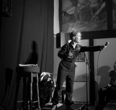 woman stands on stage and holds out a mic to the audience