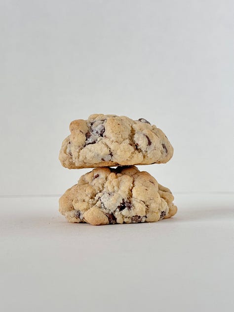 1: Two chocolate chip cookies side by side, the left propped up the right. 2: Two chocolate chip cookies, one stacked on top of the other. 3: two chocolate chip cookies stacked in a clear plastic bag tied with a white bow.