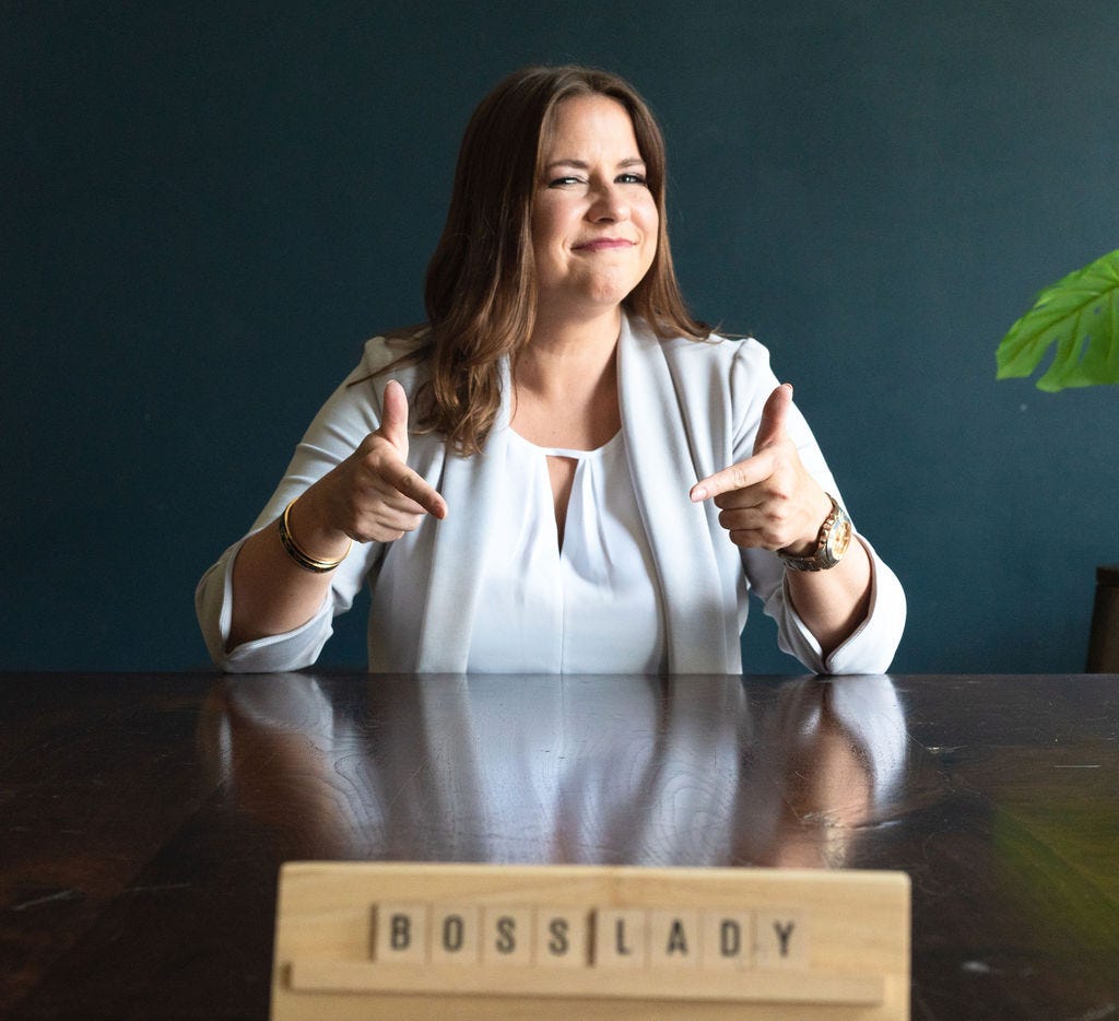 Jenny points to a sign on the desk that says Boss Lady Jenny points to a sign on the desk that says Boss Lady