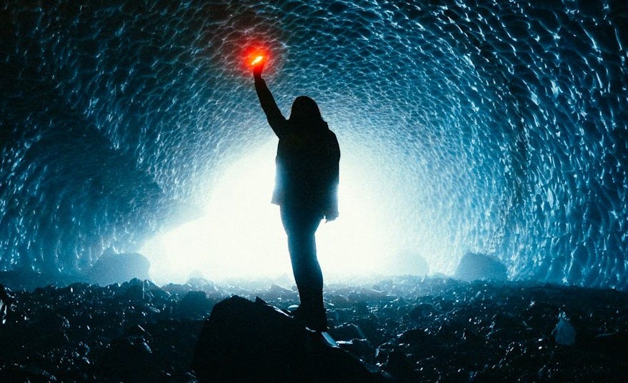 silhouette of person standing on rock with blue lights silhouette of person standing on rock with blue lights