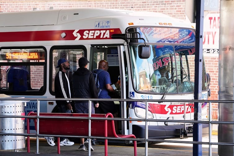 Passengers board a red, white and blue city bus