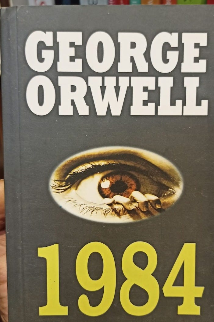 a person holding up a book in front of a book shelf