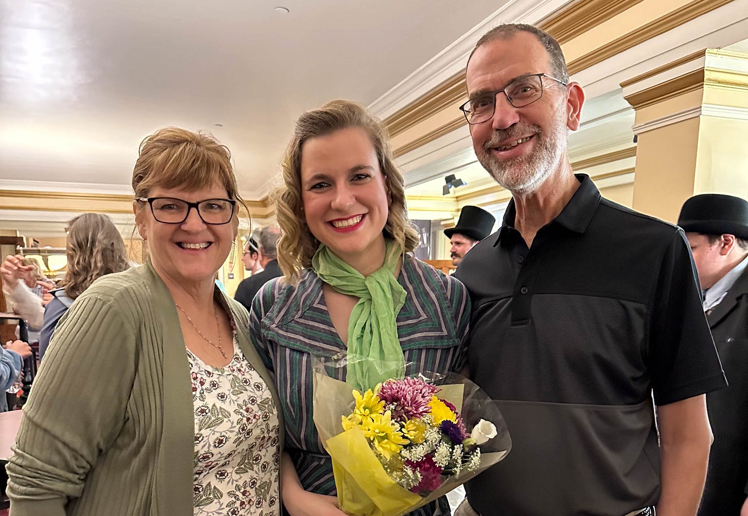 Healthy young lady holding bouquet of flowers, flanked by parents.