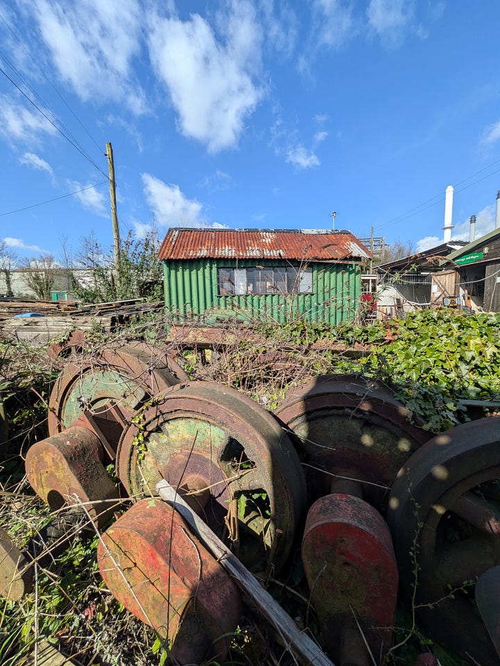 A small green steam train and some wagons, with blue sky