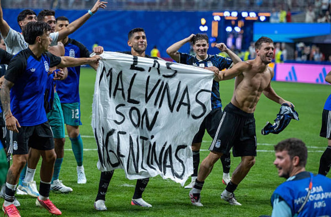 : Lisandro Martinez, Cristian Romero, Giovani Lo Celso with a banner during the FIFA World Cup 2026 Semi Final match between England and Argentina at Atlanta Stadium on July 15, 2026 in Atlanta, Georgia. The banner refers to the British Overseas Territory of the Falkland Islands, located off the coast of Argentina. Argentina disputes British sovereignty over the islands and refers to them as Las Malvinas. (Photo by Sebastian Frej/Getty Images)