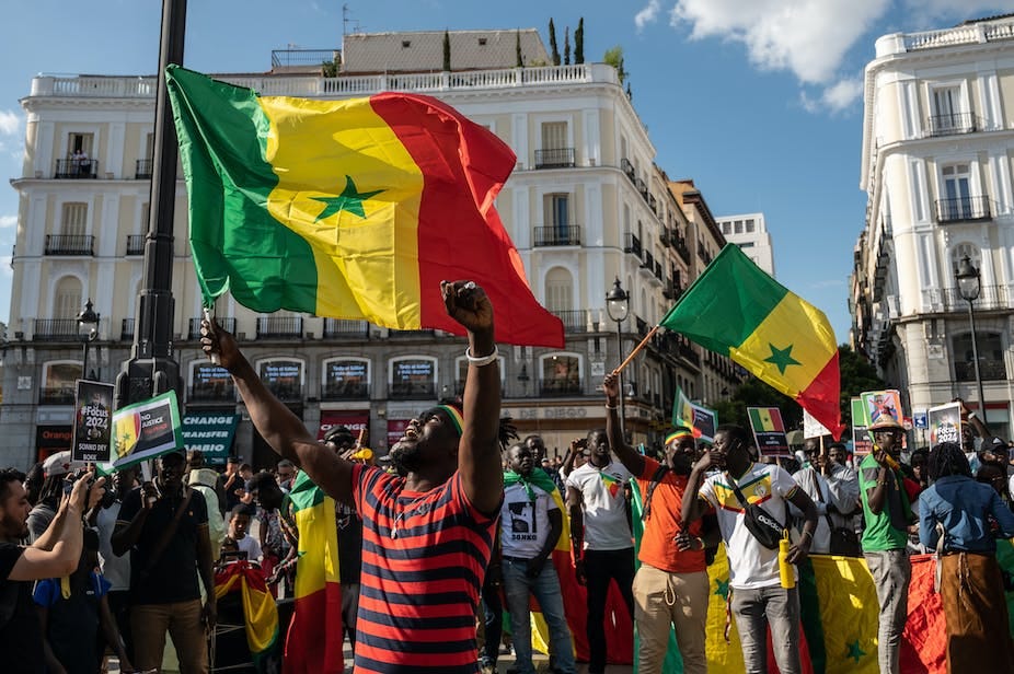 People waving Senegal flags are seen during a protest. People waving Senegal flags are seen during a protest.