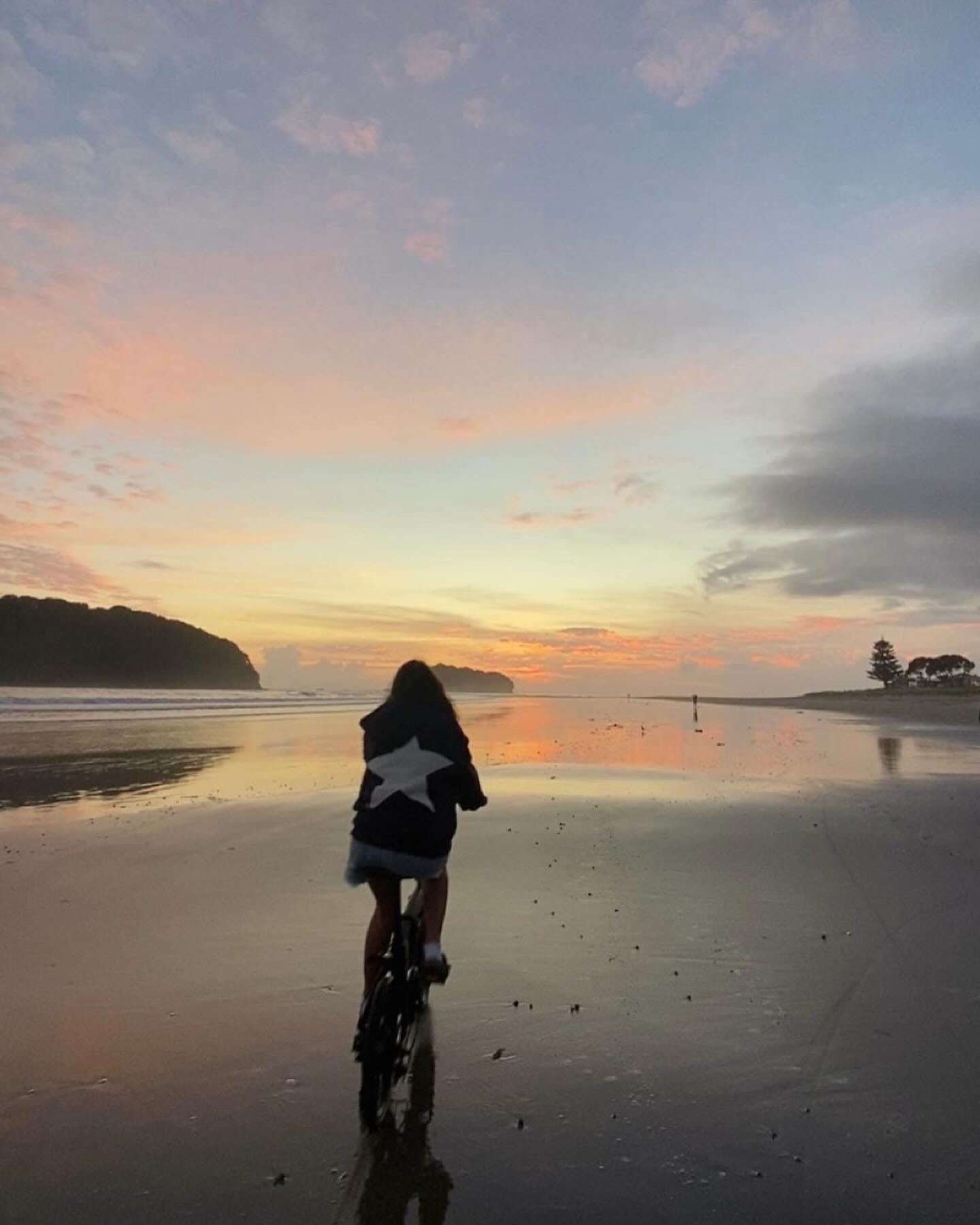 image of a person cycling on the beach at sunset