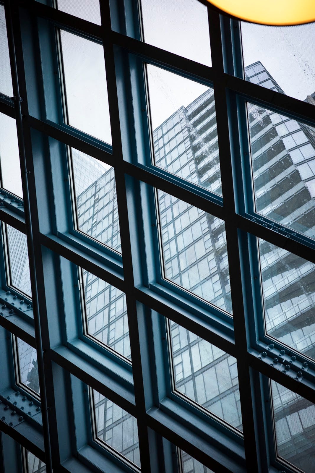 From the interior of the Seattle Public Library Central branch looking out between the latticed metal up at an adjacent skyscraper.