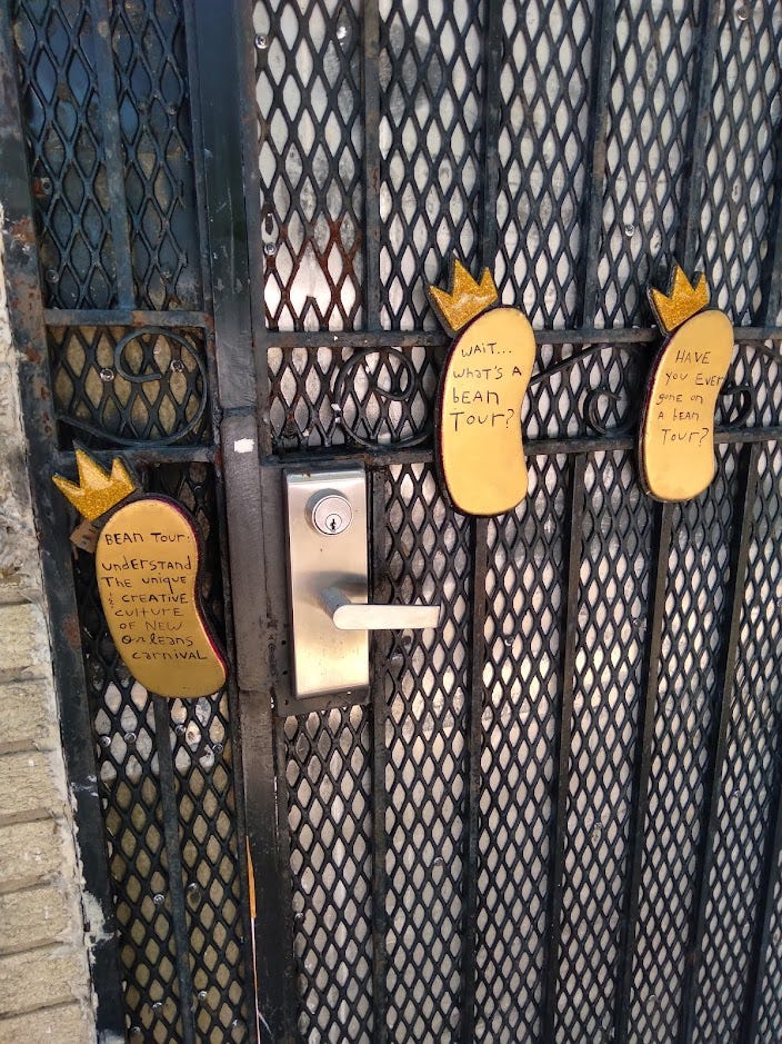 A mesh door with small golden bean-shaped signs advertising a "bean tour" relating to New Orleans Carnival.