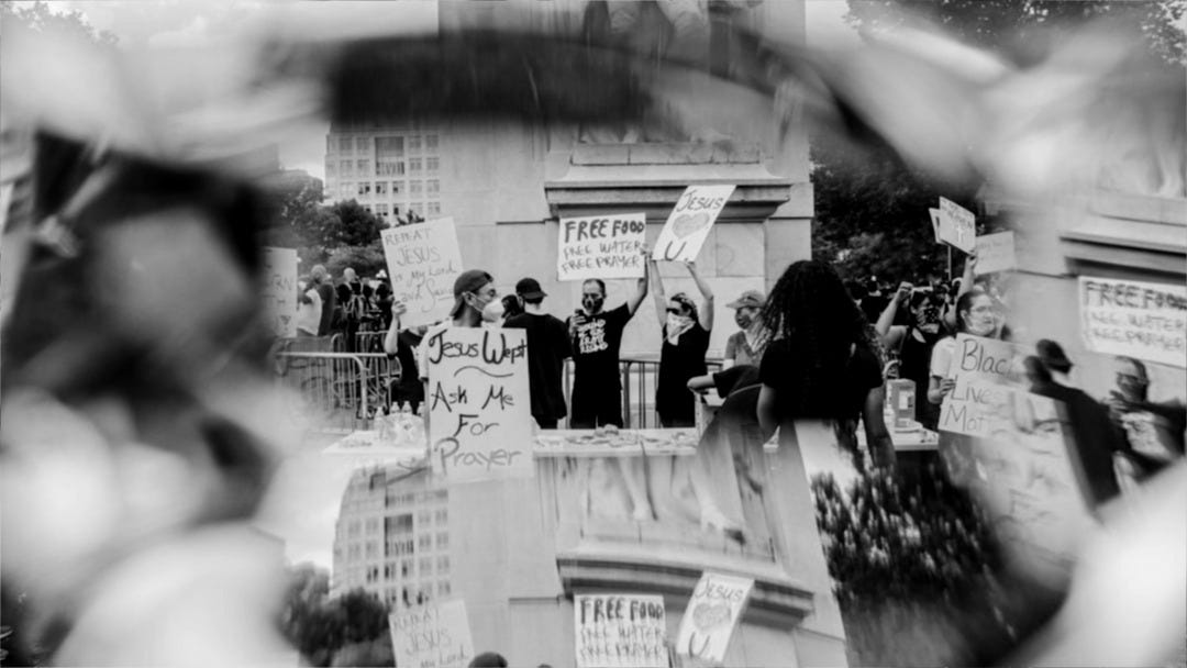 man in black suit holding white printer paper