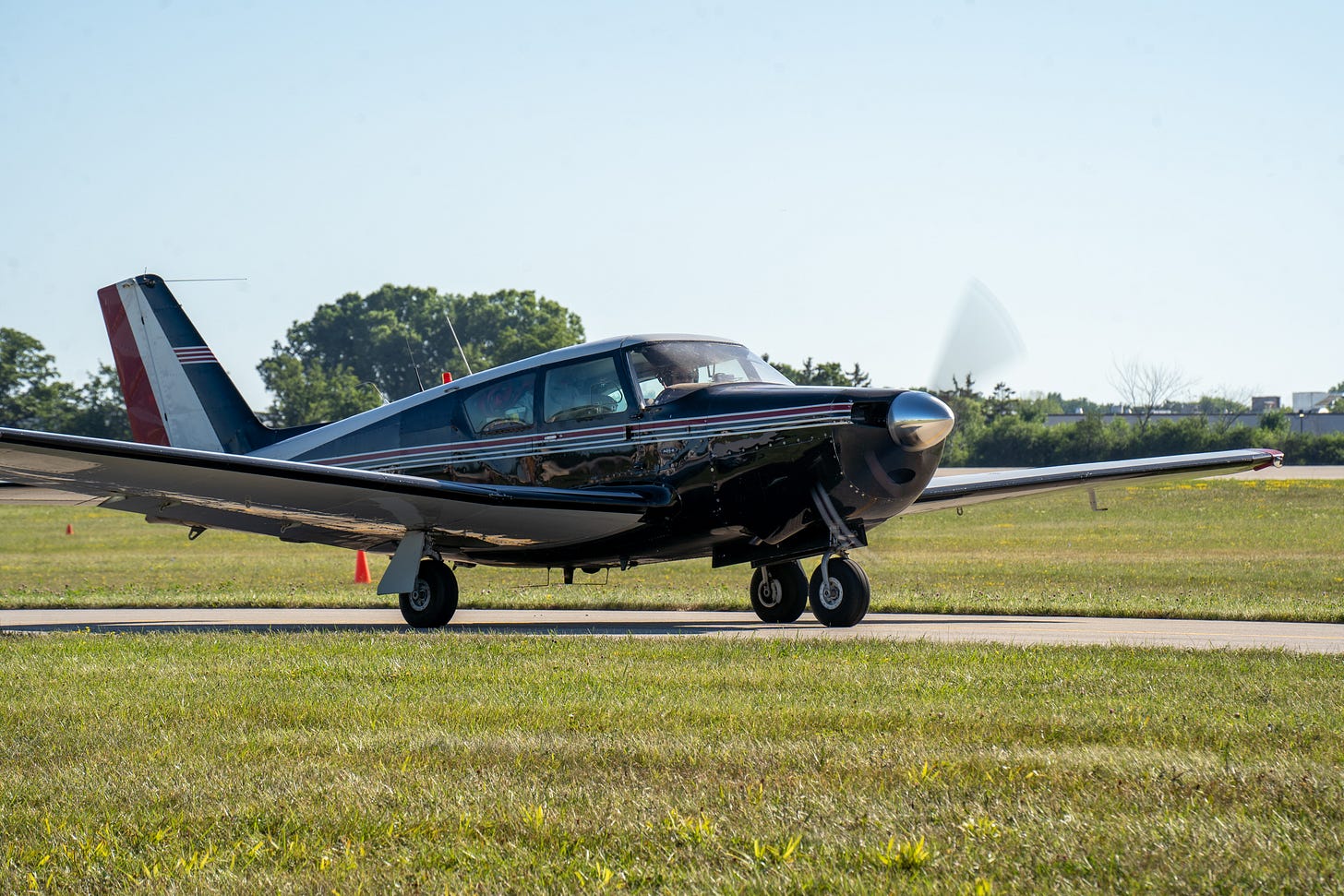 Maroon airplane with white trim taxis along the ground
