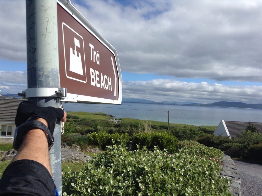 View of the sea in front of a sign pointing to the beach