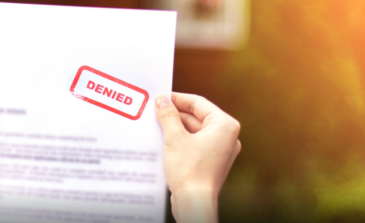 Hand holding a business letter with the word ‘denied’ prominently stamped on it Hand holding a business letter with the word ‘denied’ prominently stamped on it