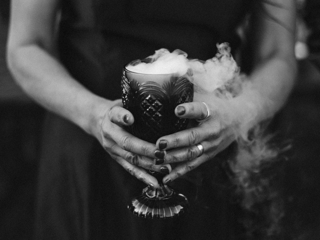 a woman in a black dress holding a cup