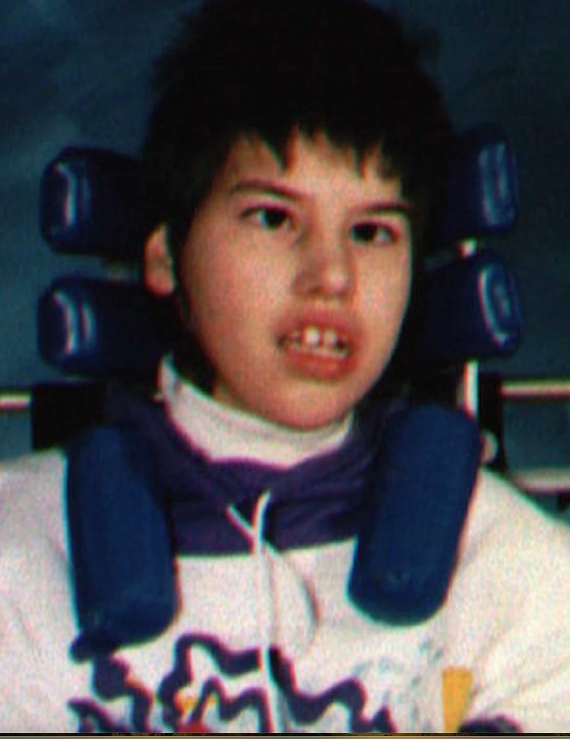 Photo of Tracy Latimer. A 12 year old girl with dark short hair and the wheelchair headrest behind her.