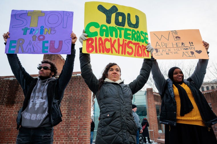 Three people hold signs next to one another