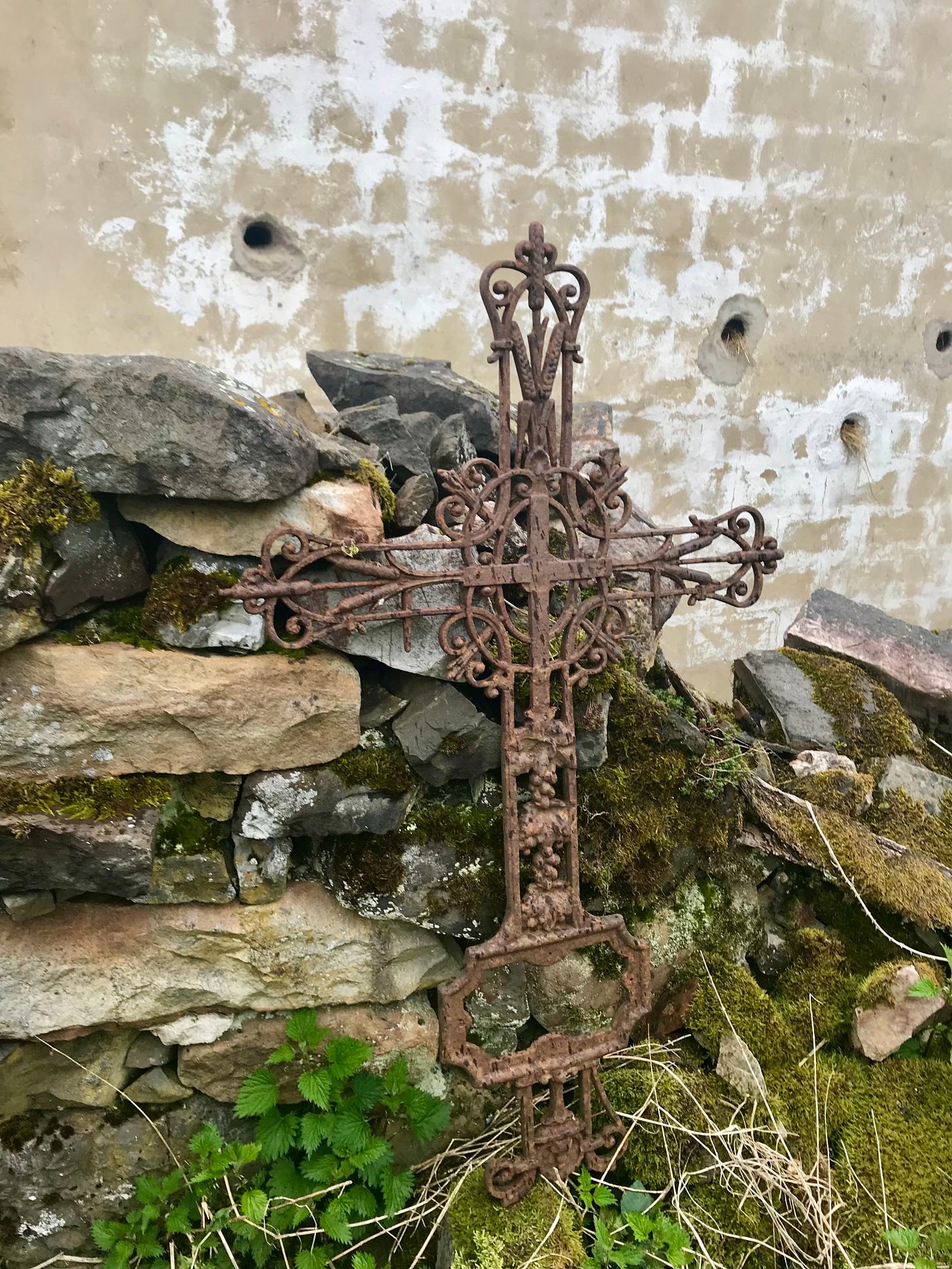Rusty cross hanging on mossy stones
