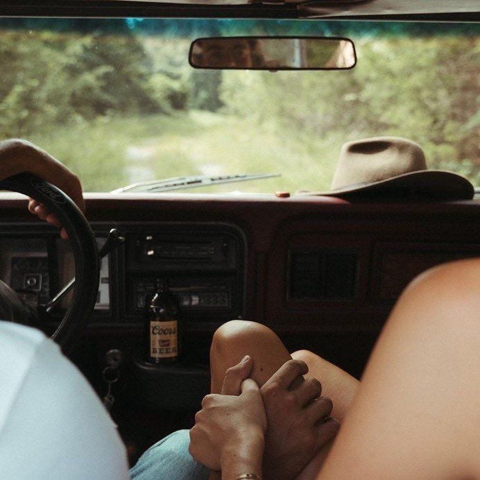 This may contain: two people are sitting in the driver's seat of a car with their feet on the steering wheel