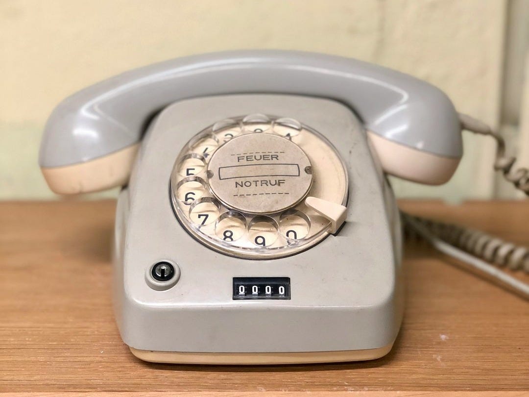 gray rotary telephone on brown table gray rotary telephone on brown table