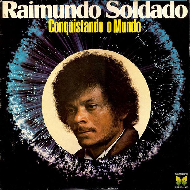 Capa do disco "Raimundo Soldado: Conquistando o Mundo". Ao fundo, fogos de artifício no céu da noite. No centro, um recorte da foto de Raimundo Soldado, um homem negro, jovem, de cabelos volumosos e bigode.