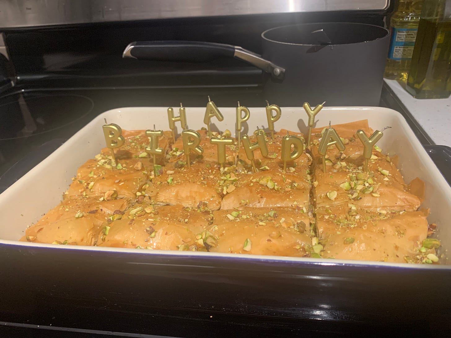 Navy ceramic tray of baklava with gold happy birthday candles.