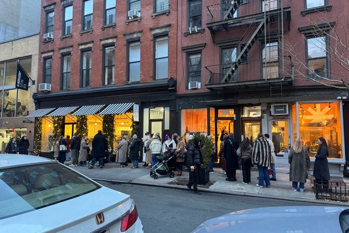 People in coats wait in front of a store in New York City. People in coats wait in front of a store in New York City.