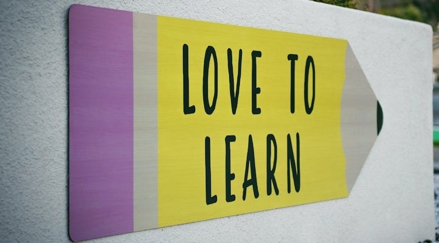 love to learn pencil signage on wall near walking man