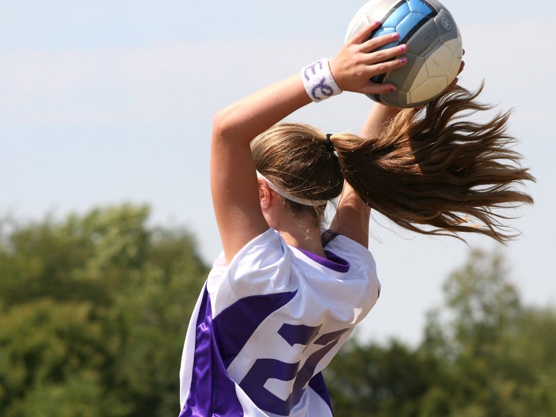 A woman in a purple and white uniform holding a white and blue ball