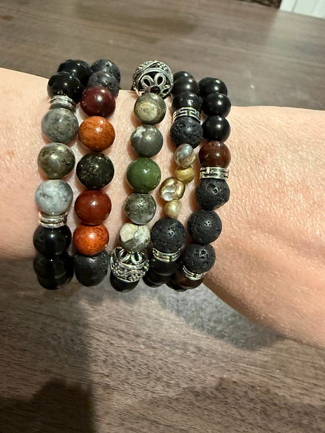 A variety of bead bracelets in various colors and pink mala beads and tiger's eye mala beads