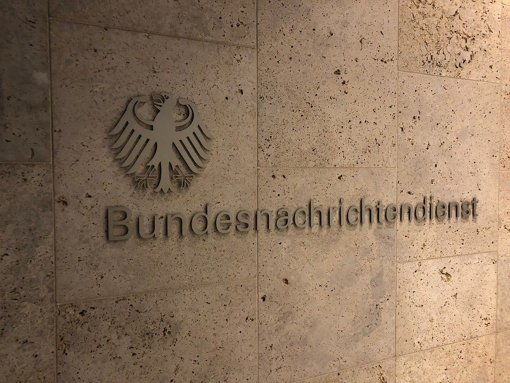 Metal eagle and Bundesnachrichtendienst lettering mounted on a textured stone wall. Metal eagle and Bundesnachrichtendienst lettering mounted on a textured stone wall.