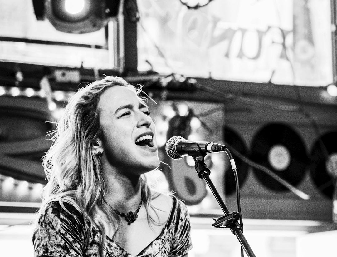 greyscale photo of woman singing inside studio