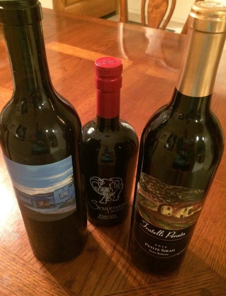 Three bottles of wine purchased at our wine tasting. They are in dark bottles with bright cork wrappers of red or gold. Three bottles of wine purchased at our wine tasting. They are in dark bottles with bright cork wrappers of red or gold.
