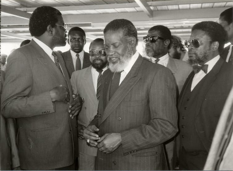 A group of men stand on their feet wearing suits and ties. A group of men stand on their feet wearing suits and ties.