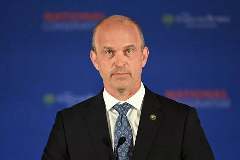 Top row left to right: Picture of bald white man wearing a dark blazer, white shirt, and patterned tie; Black woman with long hair wearing a sweater; white woman with long brunette hair wearing a white blouse. Middle row: Two Black women smiling-the woman on the left wears a dark blouse and the woman on the right wears a green shirt with a cowel, white man with short hair wears a dark blazer, white shirt and red tie. A Black man with a bald head and black beard wears a white jumpsuit top; Bottom row left to right: A white man with scraggly orange hair wears a dark blazer, white shirt, and red tie; a white man with short frown hair wears a dark blazer with a white shirt and red tie.