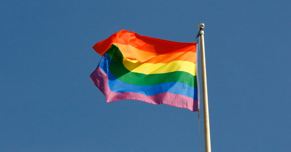 Rainbow flag waving against a clear blue sky, symbolizing LGBTQ+ pride and diversity. Rainbow flag waving against a clear blue sky, symbolizing LGBTQ+ pride and diversity.