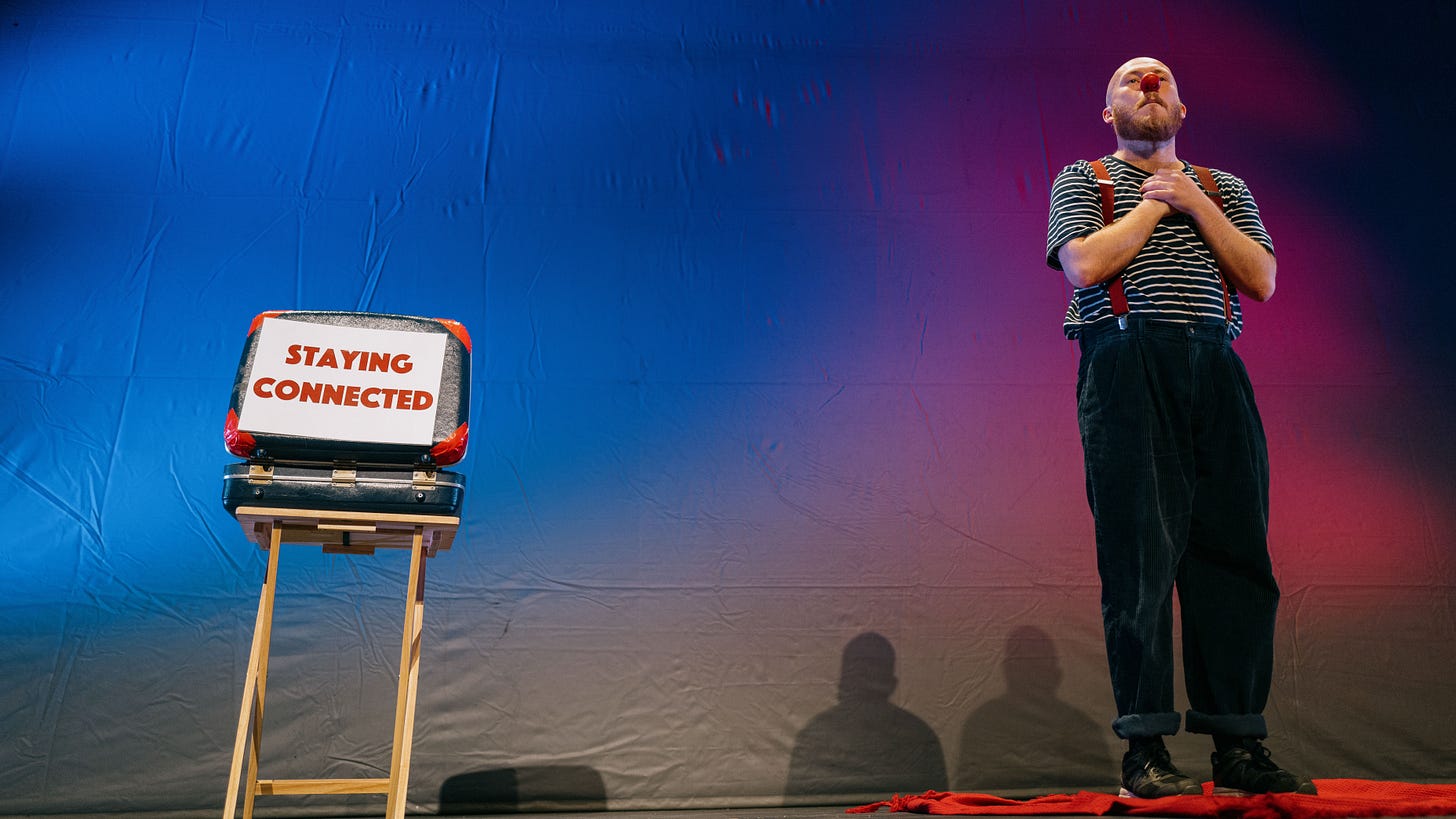 James Lewis Knight as a soulful clown with his hands on his heart, standing next to a notice saying Staying Connected.