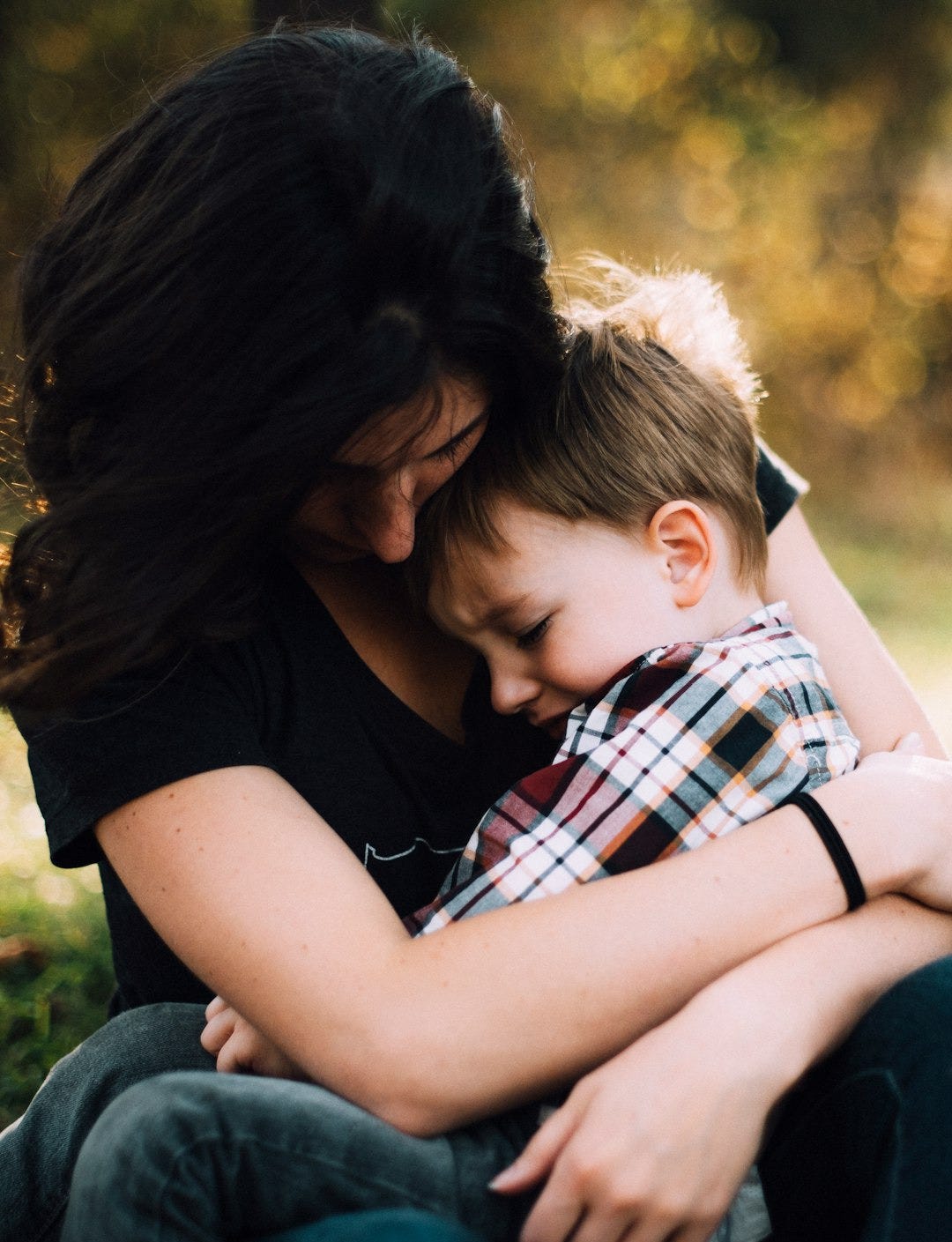 woman hugging boy on her lap woman hugging boy on her lap