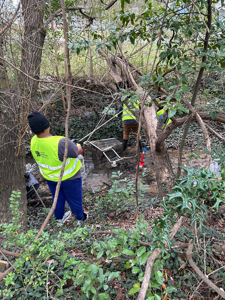 first picture: two black people in neon yellow vests in a creek pulling on a white rope pulley connected to a shopping cart. Second photo is a young man in a black hat and neon nest pulling on the rope