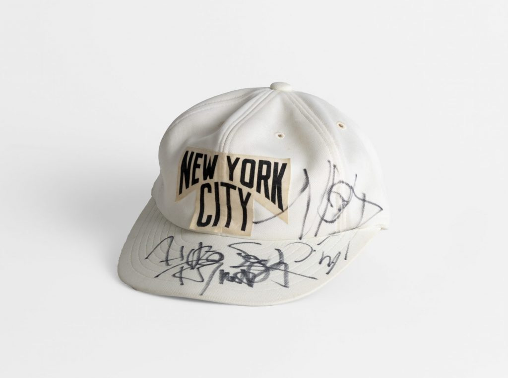 A white New York baseball cap with various signatures on it in black marker
