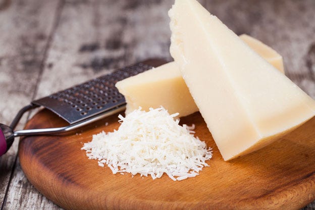 grated parmesan cheese with a microplane grater on a cutting board