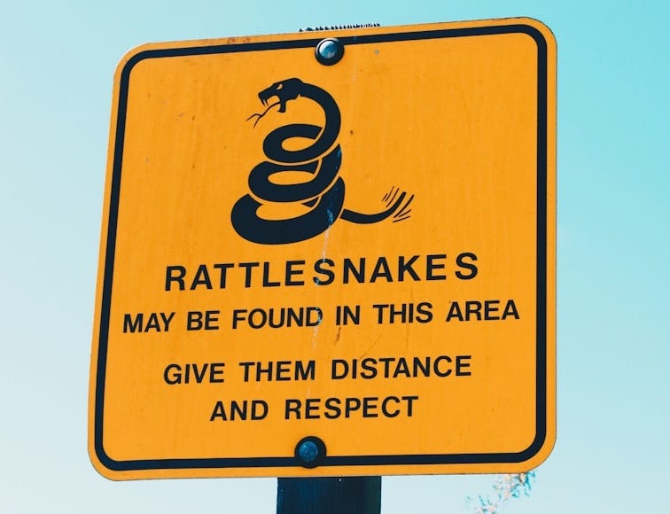 Rattlesnakes may be found in this area give them distance and respect signage