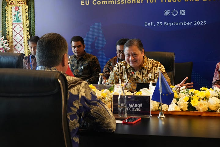 Indonesian Coordinating Minister for Economic Affairs Airlangga Hartarto shakes hands with EU Trade Commissioner Maroš Šefčovič during a bilateral meeting in Bali, September 23, 2025. Officials from both delegations are seated nearby, with flags of Indonesia and the European Union in the background.