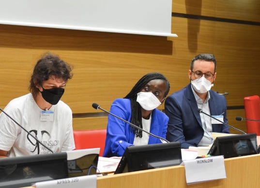 Photo à l'assemblée où on voit la députée Nadège Abomangoli assise et entourée de deux personnes, les trois personnes portent des masques FFP2, noir ou blanc