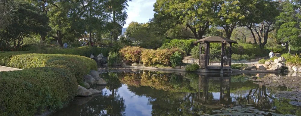 a pond with a gazebo and trees around it