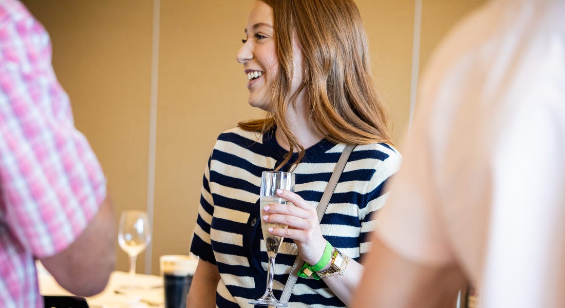 A woman with brown hair wearing a black and white striped top holding a glass of prosecco A woman with brown hair wearing a black and white striped top holding a glass of prosecco