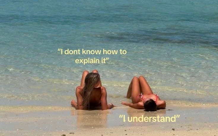 This may contain: two women laying on the beach with their backs to each other and one has her head down