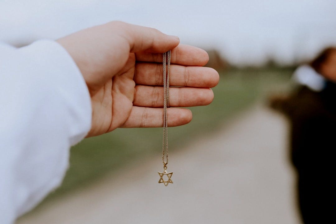 person holding gold cross pendant necklace