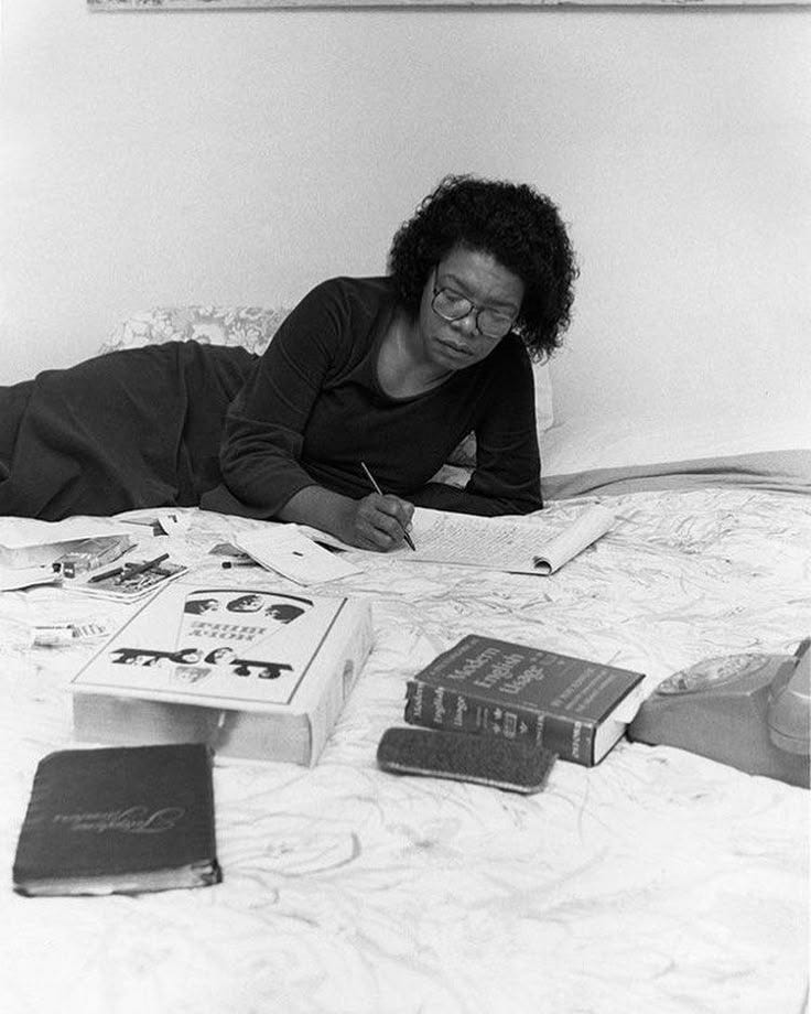 This may contain: a woman laying on top of a bed next to books