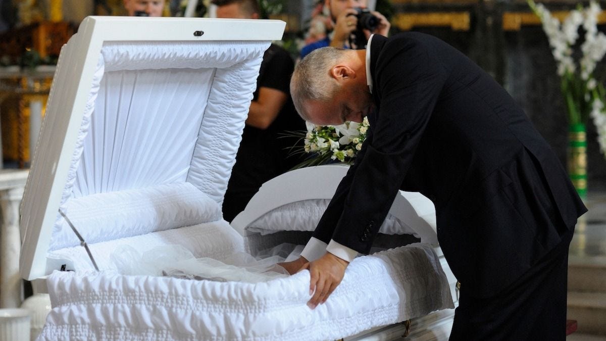 man leans over a casket